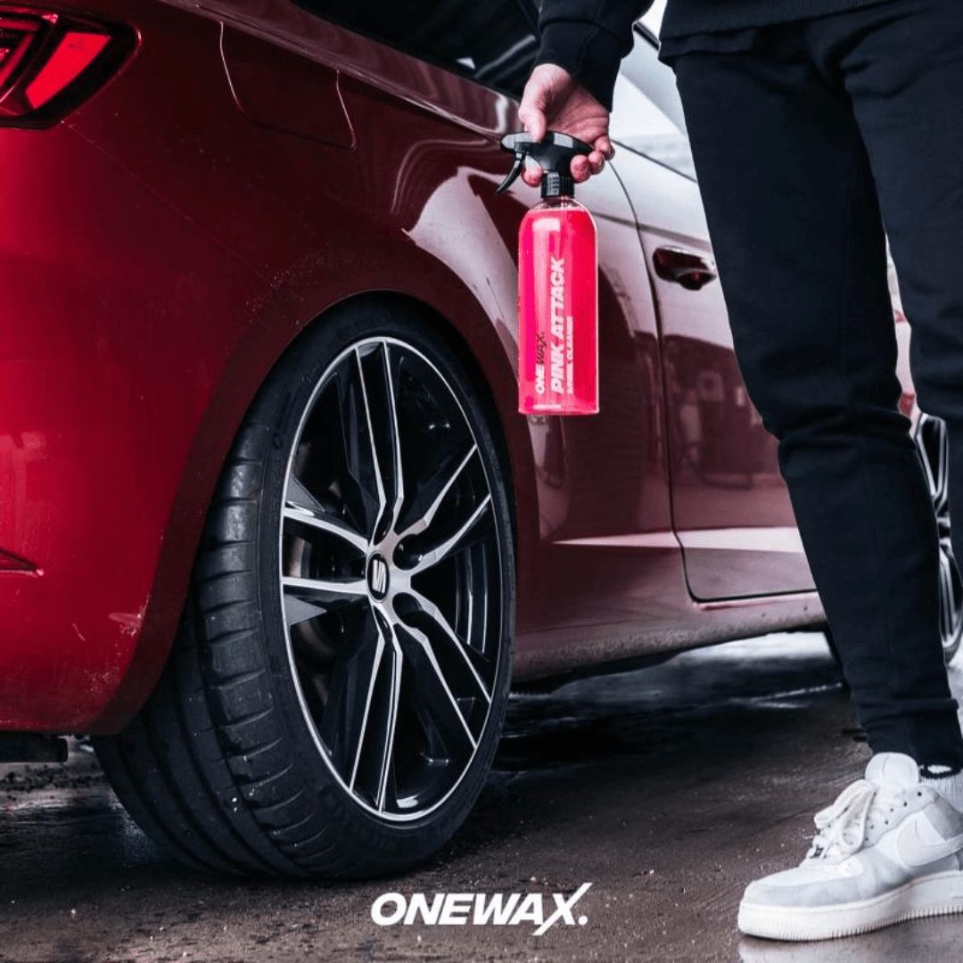 Der OneWax Pink Attack Wheel Cleaner Felgenreiniger vor einem Auto