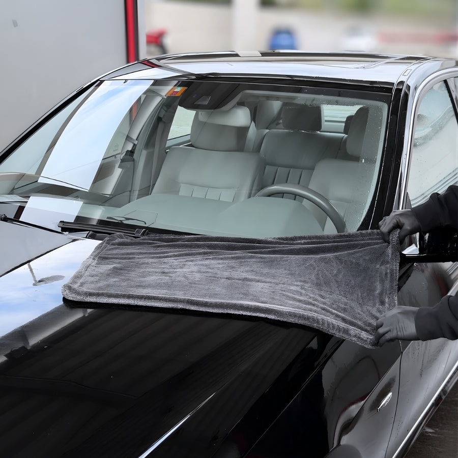 Grosses Trockentuch wird über die Windschutzscheibe eines schwarzen Autos gezogen