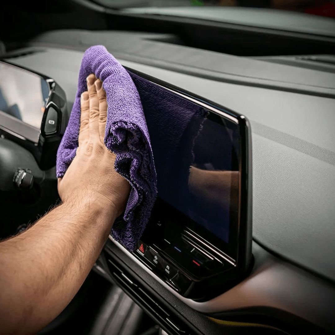 Mikrofasertuch mit Shiny Garage Interior Quick Detailer gleitet über Display im Auto