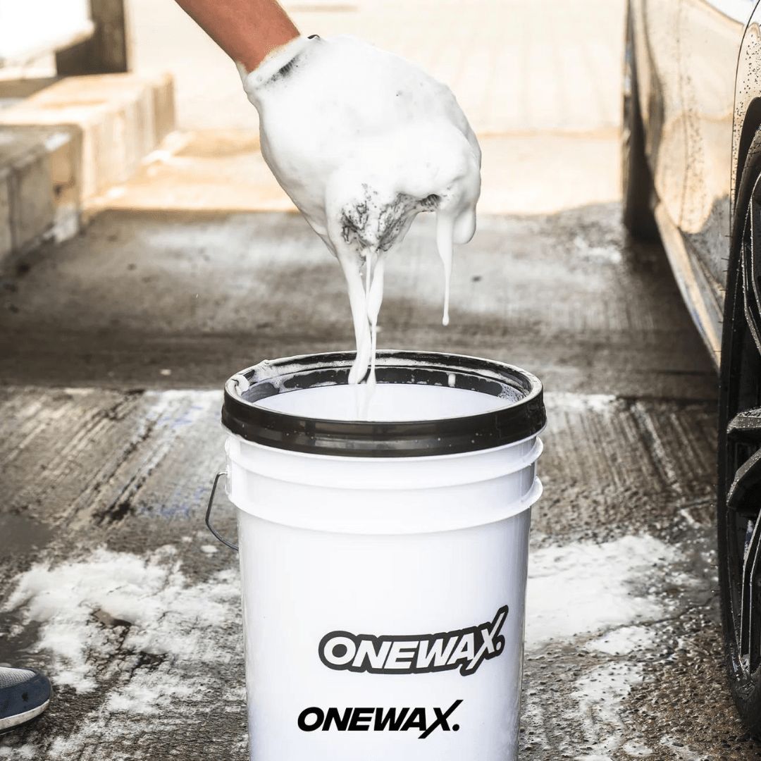 Ein Waschhandschuh über einem Eimer gefüllt mit OneWax Just Clean Car Shampoo