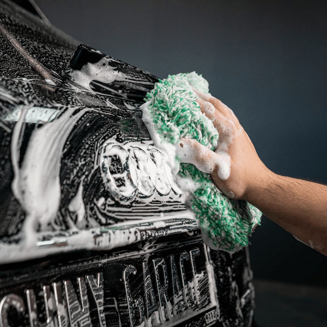 Ein Waschhandschuh gleitet mit Shiny Garage Base Shampoo Autoshampoo über die Karosserie