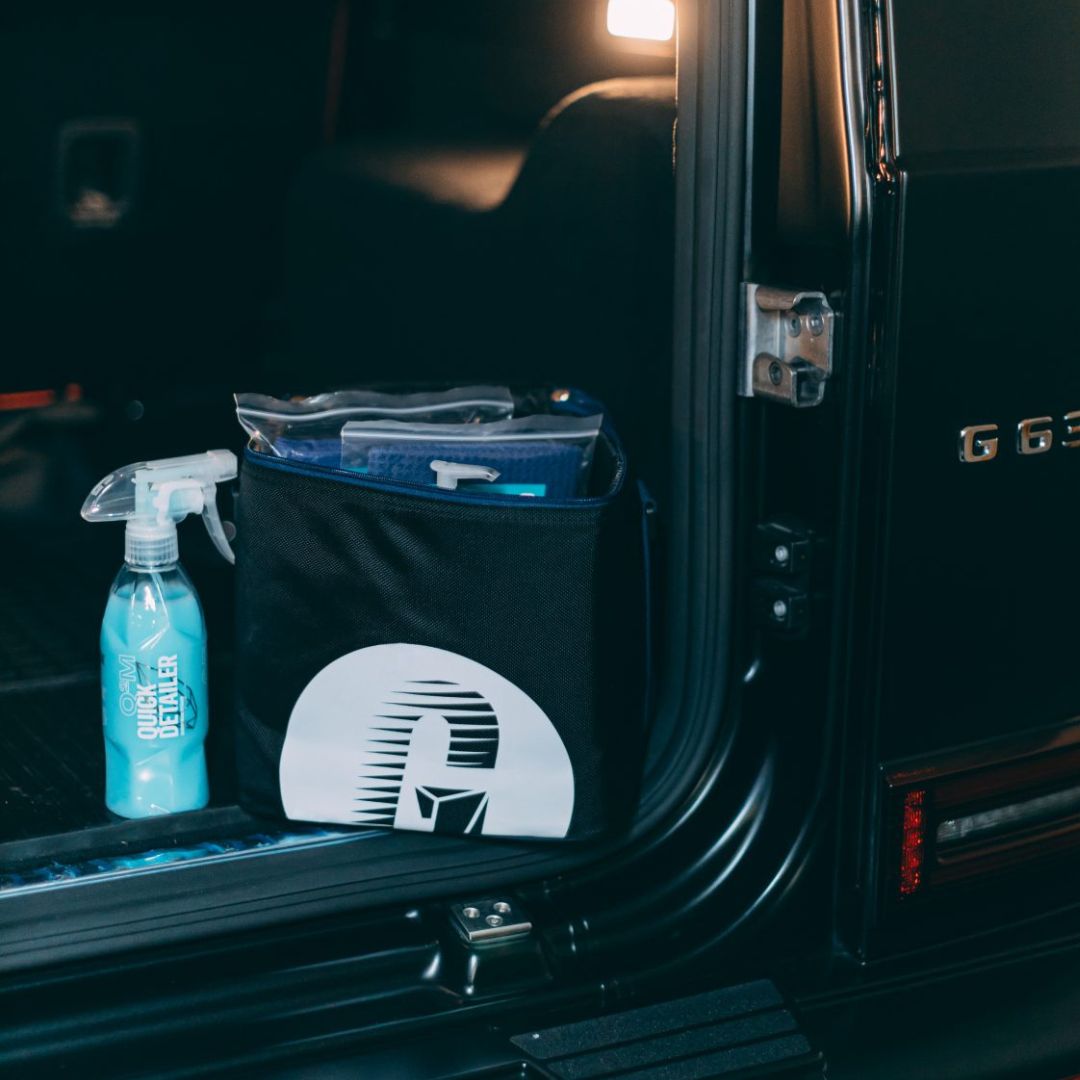 Der Gyeon Q²M QuickDetailer neben einer Tasche mit Mikrofasertücher in einem Auto
