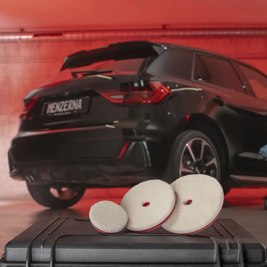 Drei Menzerna Orbital Wool Pad Polierpads vor einem Auto