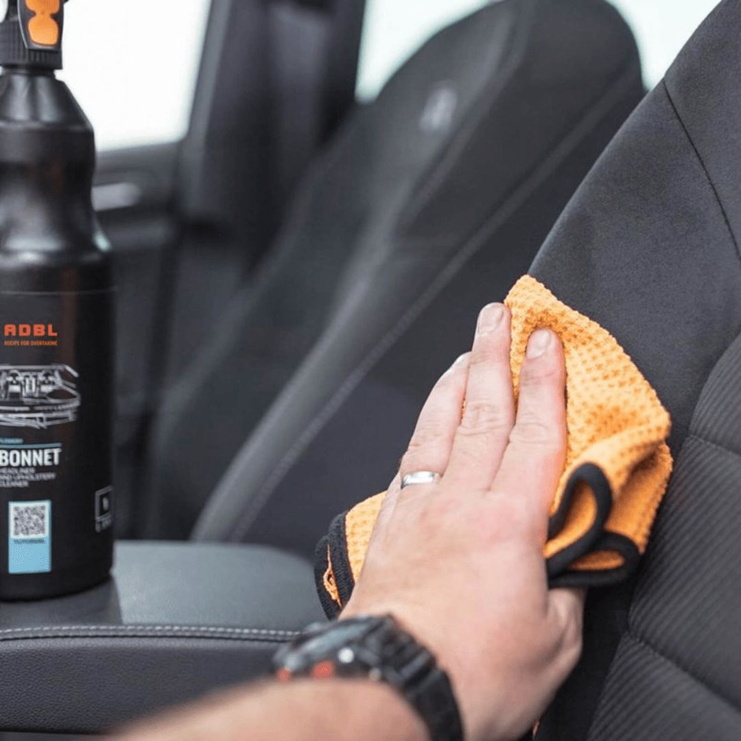 Auftragen von ADBL Bonnet Polsterreiniger mit einem Mikrofasertuch auf einen Polstersitz