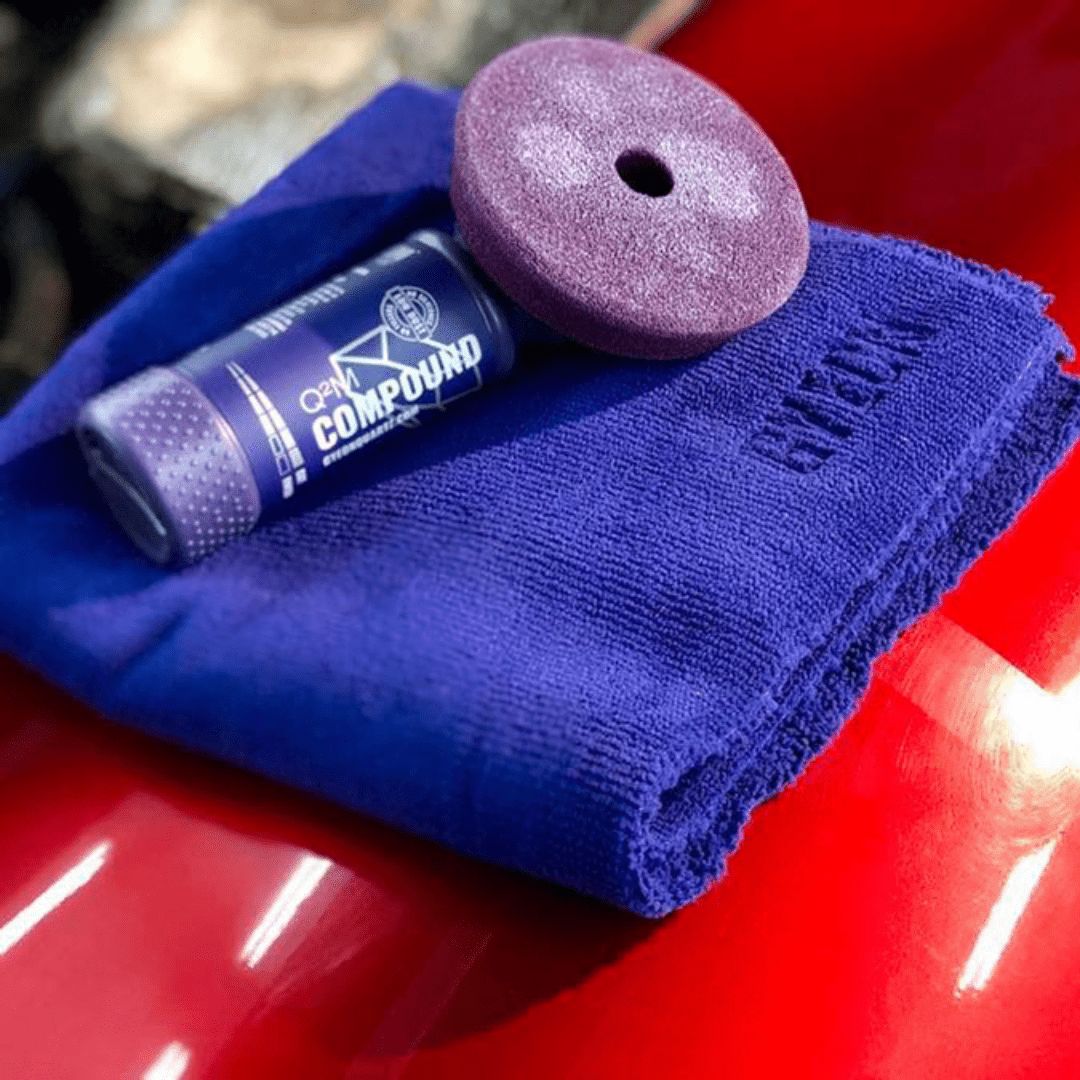 Die Gyeon Q²M Compound Politur mit einem Polierpad und Mikrofasertuch auf einem Auto