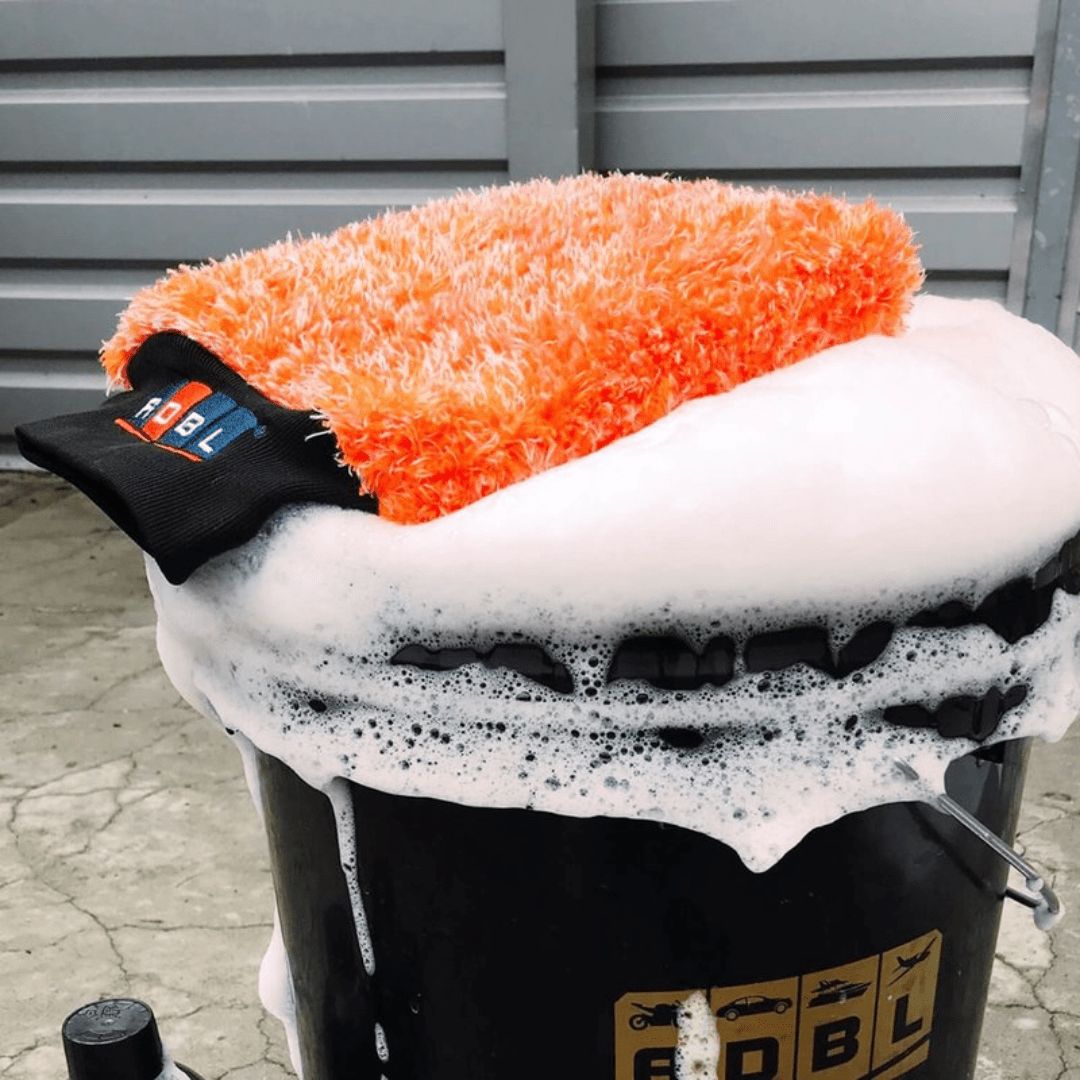 Der ADBL Caremitt Waschhandschuh auf einem Wascheimer